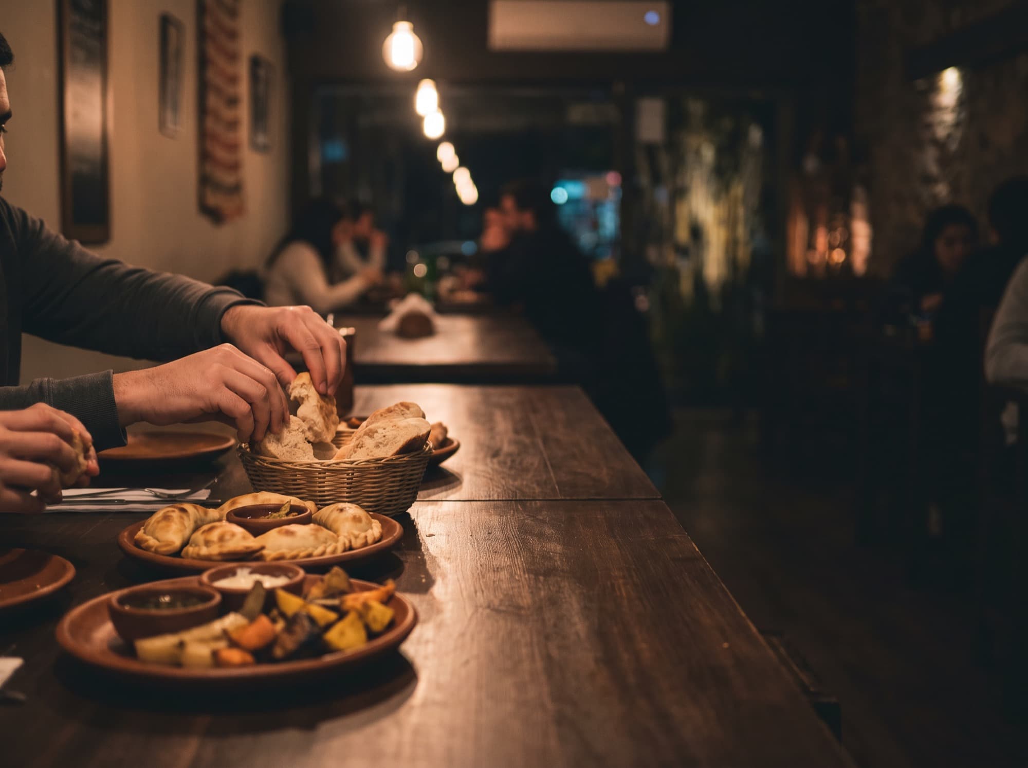 Una mesa compartida con empanadas y pan en un restaurante de barrio