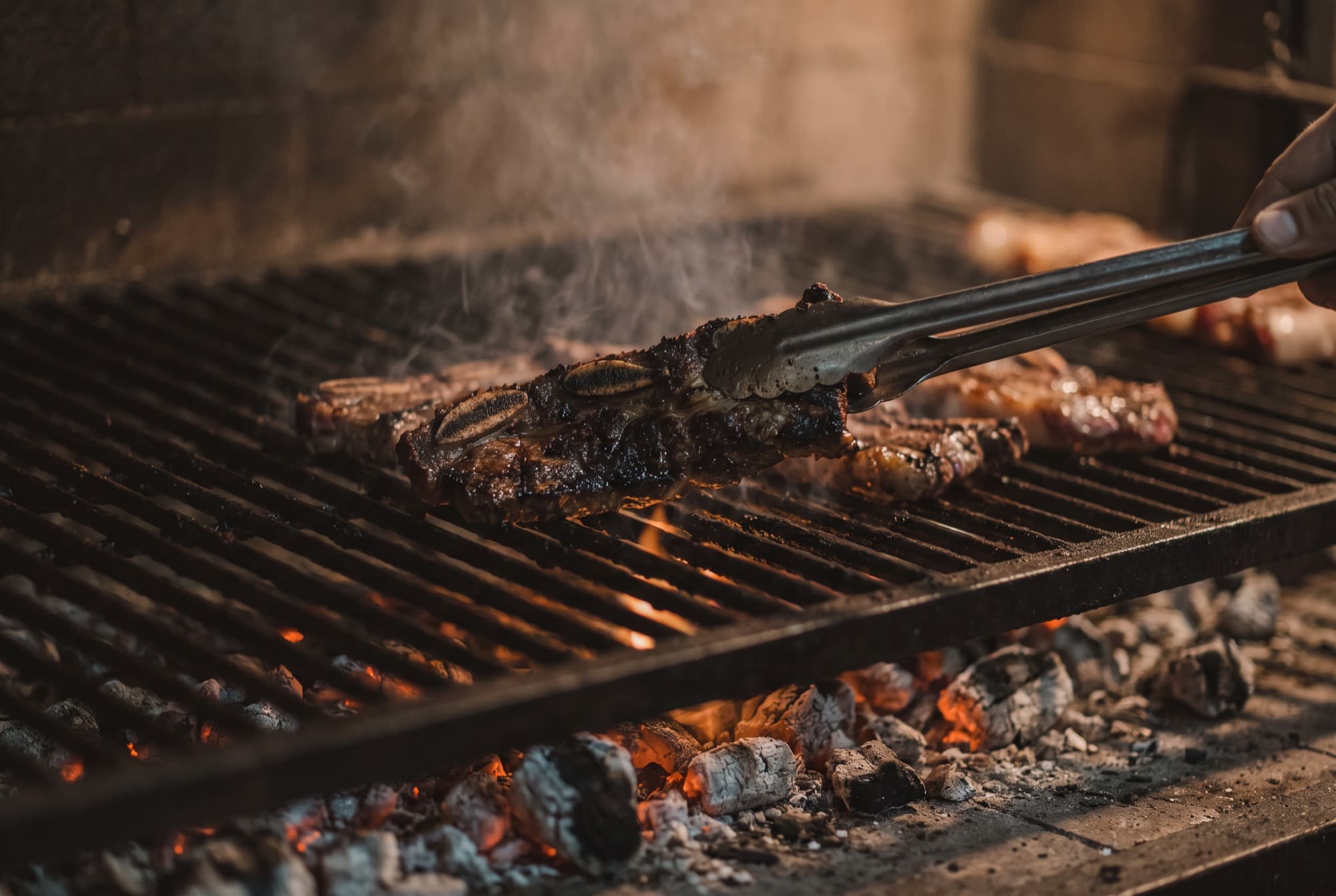 La tira de asado dándose vuelta sobre las brasas