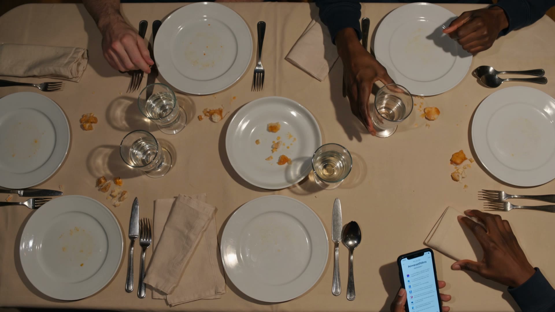 Una mesa al final de la comida, con las manos de varios comensales alrededor